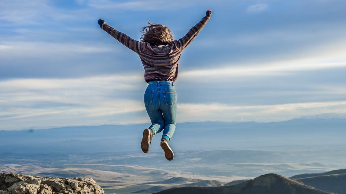 Person jumping on a mountain peak, celebrating adventure and freedom.